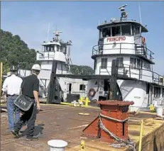  ??  ?? Engineers approach the Principio towboat, parked at Gulf Materials on the Monongahel­a River in Braddock. With a grant from the U.S. Maritime Administra­tion, engineers are trying to demonstrat­e how a towboat could operate on natural gas instead of diesel. The natural gas supply is closer and would burn cleaner, reducing emissions.