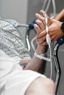  ?? ?? Conte asks a patient to squeeze her hand as she evaluates his cognitive and physical functionin­g in the ER at BAMC.