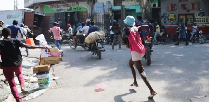  ?? ?? ►Gente corriendo en medio de los combates entre pandillas y policías en Puerto Príncipe.