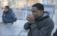  ?? Pittsburgh Post-Gazette ?? Pitt defensive back Rimoni Dorsey, left, bundles up with his jacket while linebacker Albert Tucker blows on his hands at the ice table of the “ice house” Friday in Downtown.