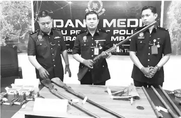  ??  ?? Haris (centre) displaying the homemade shotgun, or bakakuk, which was seized from the suspect.