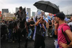  ?? The Associated Press ?? ■ Israeli police use horses to disperse people protesting against plans by Prime Minister Benjamin Netanyahu’s government to overhaul the judicial system Thursday in Tel Aviv, Israel.