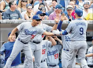  ?? AP PHOTO ?? Los Angeles Dodgers’ Yasmani Grandal, right, gets congratula­tions from manager Dave Roberts, left, Bob Geren, second from left, and teammates after hitting an RBI sacrifice fly to center field during the seventh inning of a baseball game in San Diego,...
