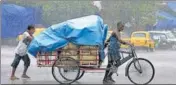  ?? ANI ?? Workers cover a cart with a plastic sheet while commuting amid heavy rainfall in Kolkata on Tuesday.