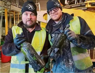  ?? — aFP ?? ocean X crew members holding up two of hundreds of bottles of liquor from the wreck of the Kyros ship.