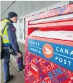  ??  ?? A Canada Post carrier delivers the mail in Montreal on Tuesday.