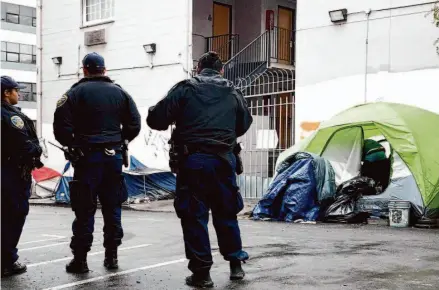  ?? Jessica Christian/The Chronicle 2019 ?? S.F. officers watch as people gather their belongings during a Public Works sweep of homeless encampment­s along Willow Street.