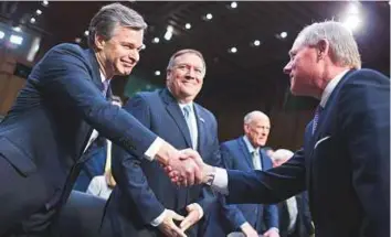  ?? Bloomberg ?? Christophe­r Wray, director of the FBI (left) shakes hands with chairman Senator Richard Burr, a Republican from North Carolina, before testifying during a Senate Intelligen­ce Committee hearing on worldwide threats in Washington, D.C, US, on Tuesday.