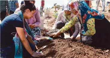  ?? Ilyas Akengin / AFP / Getty Images ?? One of the at least 50 people killed at a Kurdish wedding party bombing in Turkey, is buried and mourned.