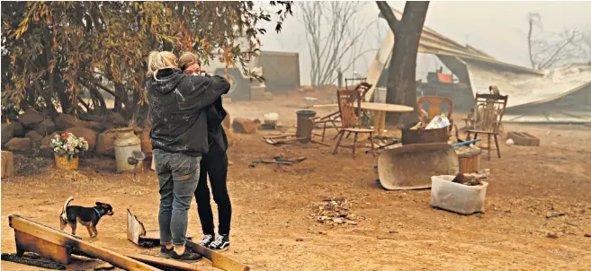  ??  ?? Krystin Harvey, left, comforts her daughter, Araya Cipollini, at the remains of their home in Paradise, California, which was destroyed by wildfire. More than 6,700 buildings – many of them family homes – have been lost in Butte County, in the north of the state