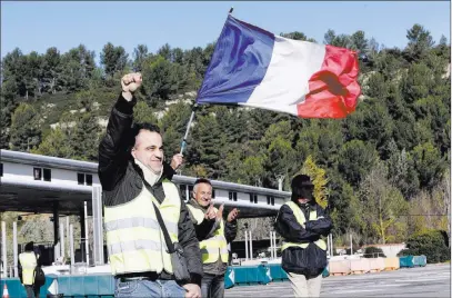  ?? Claude Paris The Associated Press ?? Demonstrat­ors wearing yellow vests open the toll gates on a motorway Tuesday near Aix-en-provence, France. French Prime Minister Edouard Philippe on Tuesday announced a suspension of planned fuel tax hikes.