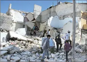  ?? AP ?? Members of the Syrian Civil Defense group and residents inspect damaged buildings Sunday after airstrikes hit the Bustan al-Qasr neighborho­od in Aleppo, Syria.