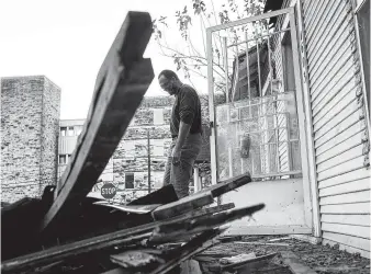  ??  ?? Gregory Luchin works to renovate a Fifth Ward house he bought to be turned into a rental property near the former St. Elizabeth Hospital, seen in the background.