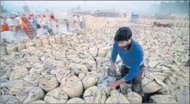  ?? AP ?? A labourer seals sacks filled with wheat in Gurdaspur in Punjab. Owing to sudden rise in temperatur­e in March when wheat crop was at maturing stage, the grain quality had suffered.