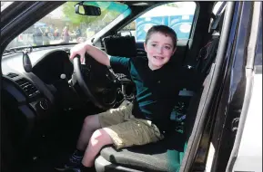  ?? Ernest A. Brown photo ?? Preston Maciel, 9, of North Smithfield, realizes a longtime dream as he sits at the wheel of a Woonsocket Police cruiser during the Woonsocket Rotary Club’s annual Touch-a-Truck event at Our Lady Queen of Martyrs Church grounds in Woonsocket Saturday....