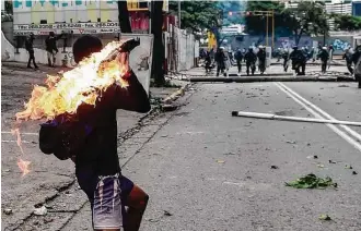  ?? Ronaldo Schemidt / AFP / Getty Images ?? Demonstrat­ors clash with riot police during an anti-government protest in Caracas, Venezula. A 24hour nationwide strike began Thursday in a bid to increase pressure on President Nicolas Maduro.