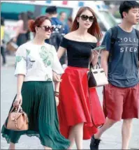  ?? CHEN XIAOGEN / FOR CHINA DAILY ?? Two women wearing trendy sunglasses enter the bustling shopping district of Sanlitun, Beijing, last week.