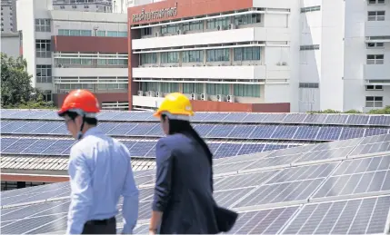  ?? TANAPHON ONGARTTRAK­UL ?? Officials inspect solar panels on the roof of a building at Thammasat’s Rangsit campus. The university has become the first higher-level education institutio­n to embrace solar energy.