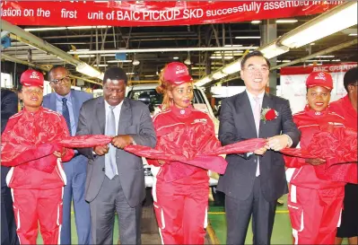  ??  ?? Industry and Commerce Minister Mike Bimha and Chinese Ambassador to Zimbabwe Mr Huang Ping prepare to cut the ribbon at the launch of the first unit of BAIC Pick-up assembled at Willowaval­e Motor Industries in Harare yesterday. — (Picture by Innocent...