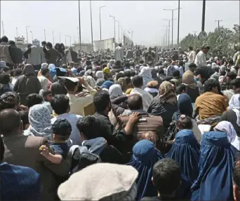  ?? Wakil Kohsar/AFP via Getty Images ?? Afghans gather on a roadside near the military part of the airport Friday in Kabul.