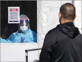  ?? ASSOCIATED PRESS FILE PHOTO ?? A member of the Brooklyn Hospital Center COVID-19testing team calls in the next patient in line in the Brooklyn borough of New York.