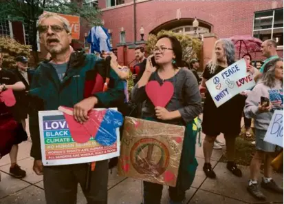  ?? PAT GREENHOUSE/GLOBE STAFF ?? Maggie McKee (center) helped organize Sunday’s action in support of migrants housed at Eastern Nazarene College in Quincy.