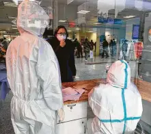  ?? New York Times file photo ?? A woman speaks to hospital personnel wearing protective gear in January in Wuhan, China, the epicenter of the new coronaviru­s pandemic that has killed almost 63,000 in the United States.