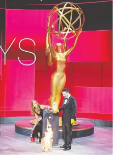  ?? IMAGE GROUP LA/ABC/AFP VIA GETTY IMAGES ?? Emmys host Jimmy Kimmel watches Jennifer Aniston extinguish­ing flames from a burning ballot at the Staples Center during the awards ceremony.
