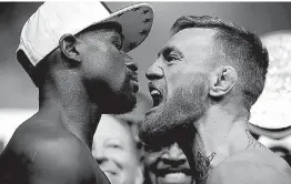  ?? Associated Press ?? n Floyd Mayweather Jr., left, and Conor McGregor face off during a weigh-in Friday in Las Vegas. The two are scheduled to fight in a boxing match tonight in Las Vegas.