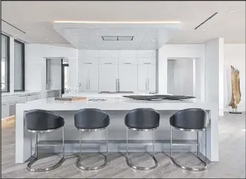  ?? Bill Hughes Real Estate Millions ?? Water’s Edge’s European-inspired kitchen features a double island, profession­algrade appliances, stark white quartz counters, and a walk-in pantry.