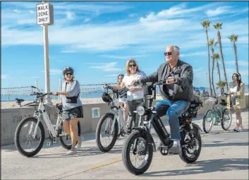  ?? Mel Melancon Los Angeles Times ?? A man rides his e-bike on the Strand at Hermosa Beach, Calif., as others walk their e-bikes in a walk-only zone. In Hermosa Beach, it’s against city code to use electric power on the Strand, but many e-bike riders do so anyway.