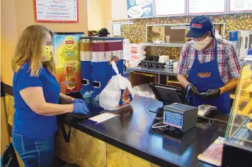  ?? ADOLPHE PIERRE-LOUIS/JOURNAL ?? Customer Karen Vance picks up an order from the Twisters at Paseo del Norte and Wyoming on May 4 while employee Brad Vermeire rings up the bill.