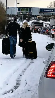  ??  ?? Trudge: Intrepid couple walk to the airport