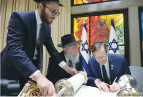  ?? (Amos Ben Gershom/GPO) ?? PRESIDENT ISAAC HERZOG writes the final letter in the Kiev Torah scroll, without the hand-guidance of a scribe.