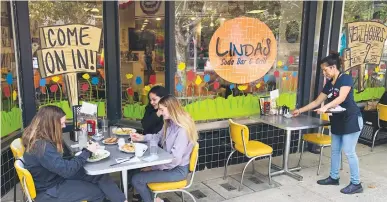  ?? Chris Kaufman/appeal-democrat ?? Chrislynnn Knittel, left, Lillian Soto and Alyssa Van Tassel, all of Yuba City, have lunch outside Linda’s Soda Bar & Grill as server Noemi Rodriguez cleans a table on Thursday in Yuba City.