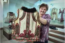  ??  ?? A woman working at the local museum shows a 100 years-old traditiona­l outfit from the Bihor northweste­rn region of Romania in Beius.