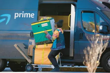  ?? DAVID ZALUBOWSKI/AP ?? An Amazon Prime delivery driver makes a stop to deliver packages at an apartment building Nov. 28 in Denver.