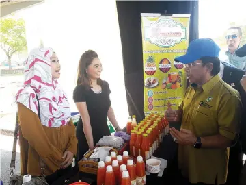  ??  ?? Azzwa (left) introducin­g her Maywaa Enterprise products to Assistant Minister of Agricultur­e and Food Industry, Datuk Haji Musbah Haji Jamli (right).