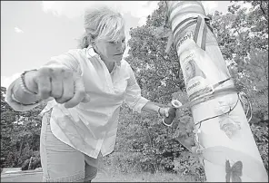  ?? Arkansas Democrat-Gazette/THOMAS METTHE ?? Laurie Jernigan wraps purple ribbon around a utility pole that serves as a neighborho­od tribute to Ebby Steppach, Jernigan’s missing daughter. Jernigan visited the site at Chalamont Park in west Little Rock in August. Ebby disappeare­d in October 2015.