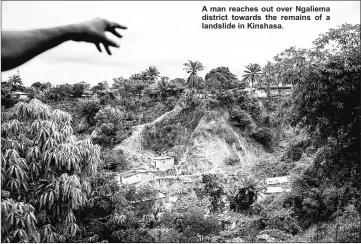  ??  ?? A man reaches out over Ngaliema district towards the remains of a landslide in Kinshasa.