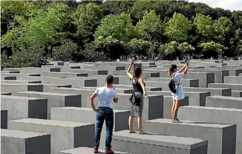  ??  ?? At a place honouring the memory of the Nazis’ victims, young laughing visitors hop from block to block, searching for the best angles.