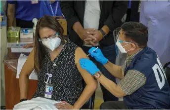  ?? — AFP photo ?? Health Secretary Francisco Duque III (right) administer­s the Sinovac vaccine on Eileen Aniceto, medical doctor of the Lung Center of the Philippine­s, in Quezon City.