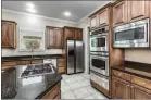  ?? ?? A chef's kitchen features a stainless-steel gas cooktop, double wall ovens and more.