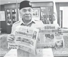  ??  ?? Isran holds up thesundayp­ost and Utusan Borneo in his office.