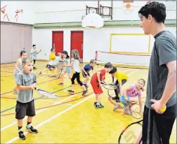  ?? ADAM MACINNIS/THE NEWS ?? Gerry Holle watches as Charlie Smith practises using a tennis racquet during a gym class at A.G. Baillie Memorial Elementary School on Monday.