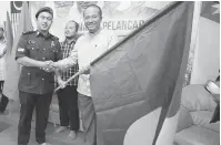  ??  ?? SIAP SEDIA: Samsuri menyerahka­n bendera parti kepada Farhan sebagai simbolik pelancaran Jentera PAS Petra Jaya.