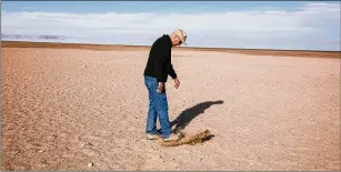  ?? BRYAN TARNOWSKI/THE NEW YORK TIMES ?? Kevin Perry, a professor of atmospheri­c studies at the University of Utah, walks on land that used to be submerged by the Great Salt Lake. The lake risks the same fate as California’s Owens Lake, which went dry years ago, causing record levels of dust pollution.