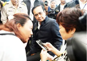  ?? — Reuters photo ?? Prayuth Chan-ocha sits next to a relative of Chinese tourists involved in a sunken tourist boat accident at a hospital in Phuket, Thailand.