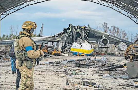  ?? ?? Left: Mariya, 77, whose daughter and son-in-law died under the rubble of a building destroyed by Russian shelling, cries in Borodyanka, northern Ukraine. Above: a Ukrainian soldier looks at the destroyed cargo plane Antonov An-225 Mriya at Gostomel airport near Kiev. The biggest cargo plane in the world, it was shelled by Russian forces during their occupation of the airport. Right: a farmer wears a bulletproo­f vest during crop sowing in Zaporizhzh­ia region, 20 miles from the front line