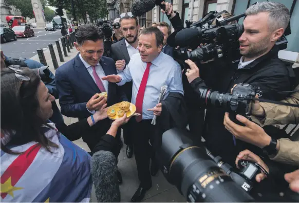  ?? Getty ?? Arron Banks, centre, and Andy Wigmore, left, are given meat pies by a pro-EU protester after they were questioned by MPs over links to Russia and ‘fake news’